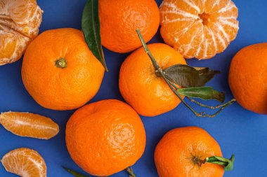 Tasty tangerines with leaves on blue background