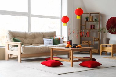 Mandalinalı kahve masası, çay seti ve şenlikli oturma odasında yerde yastıklar. Çin Yeni Yıl Kutlaması