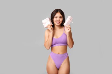 Gri arka planda hediye kutuları olan güzel, mutlu, Asyalı bir kadın. Uluslararası Kadınlar Günü