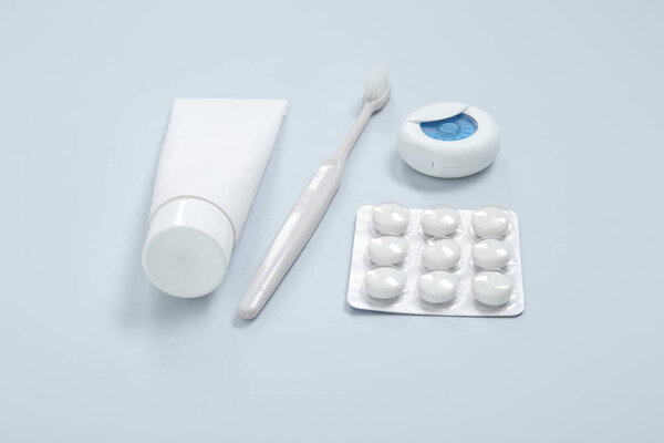 Зубная паста с щеткой, зубной нитью и жевательной резинкой на сером фоне