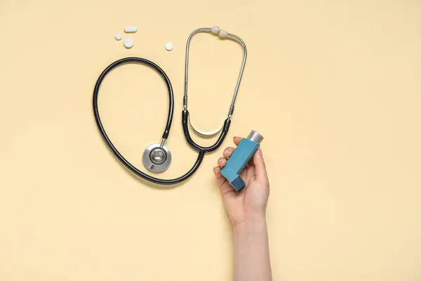Weibliche Hand Mit Asthma Inhalator Stethoskop Und Pillen Auf Gelbem — Stockfoto