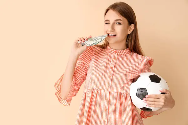 Young woman with soccer ball and money on beige background. Sports bet concept