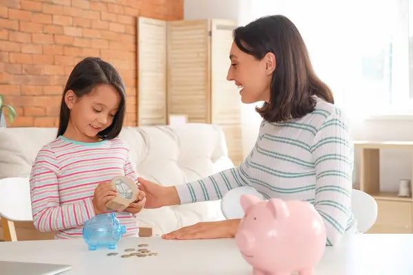 Little girl with piggy bank and her mother at home