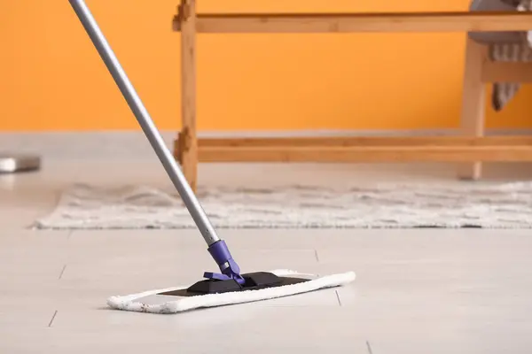 Cleaning of wooden laminate floor with mop in living room