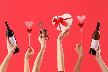 Şarap şişeleri, tirbuşon, hediye ve kırmızı arka planda kalpleri olan kadınlar. Sevgililer Günü kutlaması