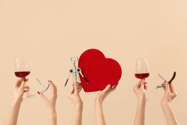 Şarap kadehleri, hediye ve bej arka planda tirbuşonu olan kadınlar. Sevgililer Günü kutlaması