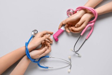 Astım spreyi ve beyaz arka planda steteskoplarla çocuk elleri.