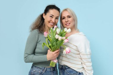 Mavi arka planda bir buket güzel lalesi olan olgun kadınlar. Uluslararası Kadınlar Günü