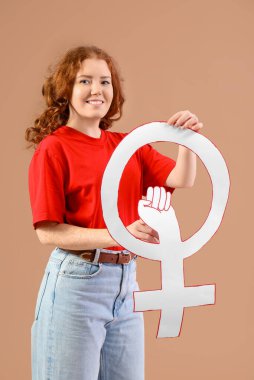 Bej arka planda, yumruğunu sıkmış, elinde cinsiyet sembolü olan güzel bir genç kadın. Kadın tarihi ayı