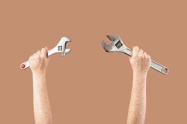 Bej arka planda ayarlanabilir ingiliz anahtarı olan kadın eller. Kadın tarihi ayı