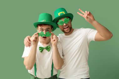 Yeşil arka planda cüce şapkalı ve parti gözlüklü mutlu genç adamlar. Aziz Patrick Günü kutlaması