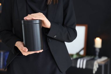 Cenaze töreninde elinde morg vazosuyla yas tutan genç kadın, yakın plan.