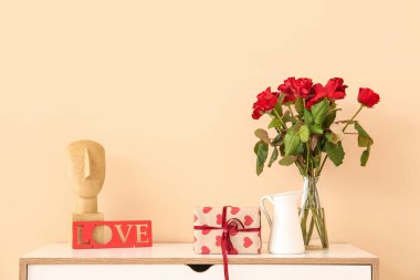 İçinde hediye kutusu olan çekmeceler, bir buket gül ve bej duvarın yanında dekor. Sevgililer Günü kutlaması