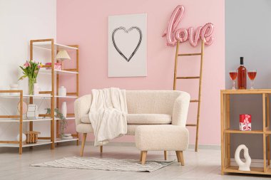 Beyaz kanepeli şenlikli oturma odasının içi, Sevgililer Günü kutlamaları için balonlardan ve dekorasyonlardan yapılmış aşk sözcüğü.