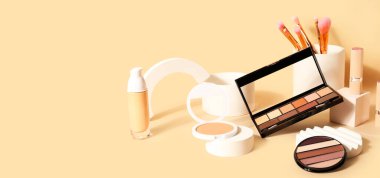 Bej arka planda dekoratif kozmetik, fırçalar ve podyumlar metin için alan