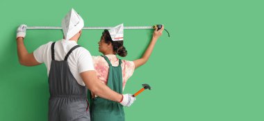 Yeşil duvarın yanında mezurası olan genç bir çift. Tasarım için pankart