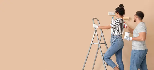 Young couple painting beige wall. Banner for design