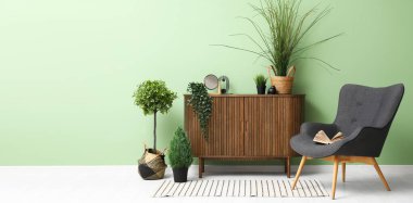 Gri koltuğu, ahşap dolabı, çiçekleri ve çizgili halısı olan oturma odası. Tasarım için pankart