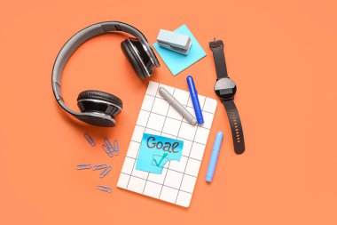 Kırmızı arka planda kelime golü, kırtasiye, kulaklık ve akıllı seğirme ile yapışkan not