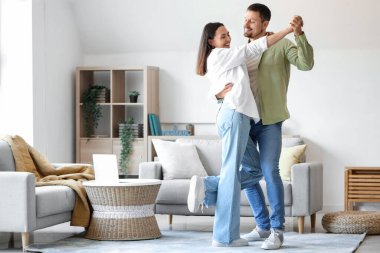 Mutlu genç çift evde dans ediyor.