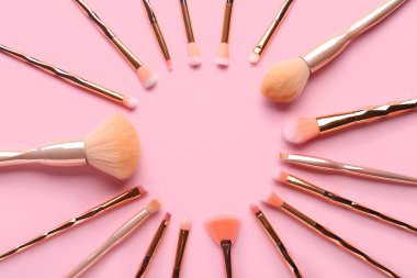 Pembe arka planda farklı makyaj fırçalarından yapılmış çerçeve