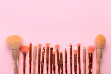 Pembe arka planda farklı makyaj fırçaları olan kompozisyon