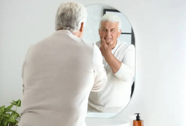 Senior man looking in mirror at home