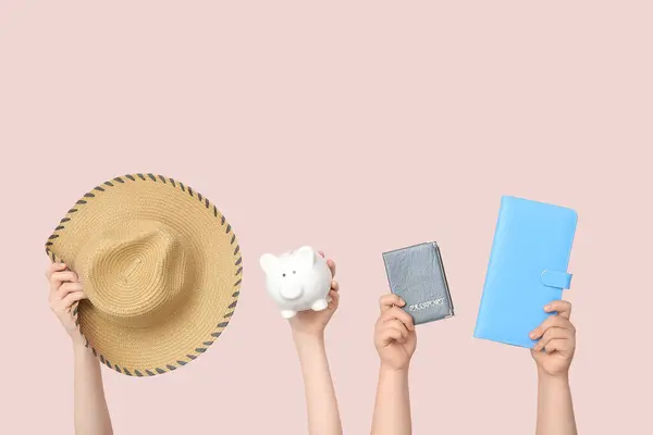 Female hands with hat, passport, piggy bank and wallet on beige background. Travel concept
