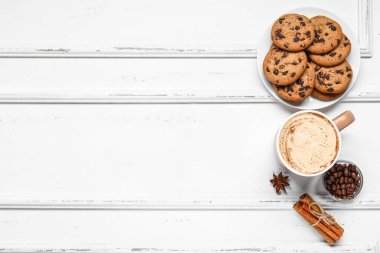 Tarçınlı kahve ve beyaz ahşap arka planda kurabiyeler.