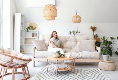 Oturma odasındaki kanepede oturan yastıklı genç kadın.