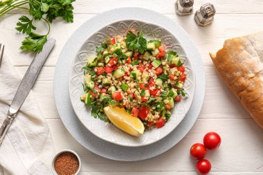 Lezzetli tabakta salata ve hafif ahşap arka planda ekmek.