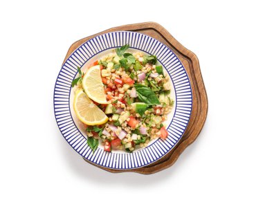 Lezzetli tabakta salata ve beyaz arka planda limon dilimleri.