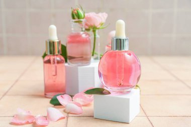 Bej kaplama arka planda gerekli yağ şişeleri ve gül yapraklarıyla sıva podyumlar