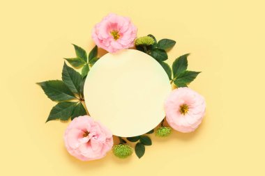 Boş kağıt çarşaflı kompozisyon, yeşil yapraklar ve bej arka planda güzel çiçekler.