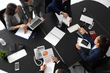 İş adamları konferans salonundaki masada pazarlık ediyorlar.