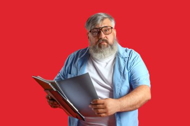 Kırmızı arka planda not defterleri olan olgun bir adamdan korkuyorsun.