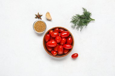 Bir kase salamura domates ve beyaz arka planda farklı baharatlar.