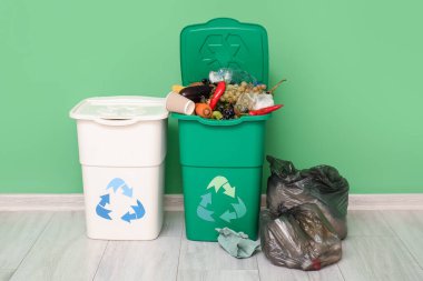 Yeşil duvarın yanında çöp konteynırları ve çöp torbaları var. Geri dönüşüm kavramı
