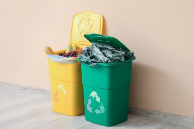 Bej duvarın yanında farklı çöp kutuları var. Geri dönüşüm kavramı