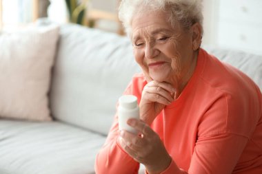 Evinde ilaç şişesi olan düşünceli, son sınıf öğrencisi bir kadın.