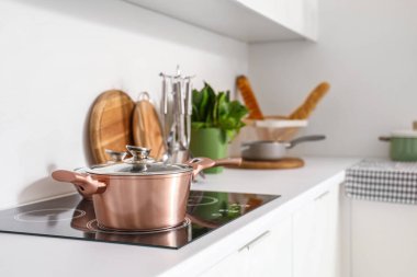 Modern mutfağın içinde çatal bıçak ve elektrikli soba beyaz tezgahlarda.