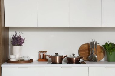 Modern mutfağın içinde çatal bıçak ve elektrikli soba beyaz tezgahlarda.