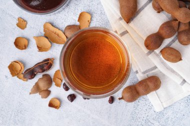 Bir bardak lezzetli demirhindi suyu ve beyaz arka planda meyveler.