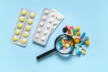 Mavi arka planda farklı haplar içeren büyüteç