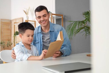 Genç bir adam ve küçük oğlu evde kitap okuyorlar.