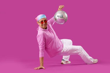 Havalı olgun bir adam, disko topuyla mor arka planda dans ediyor.