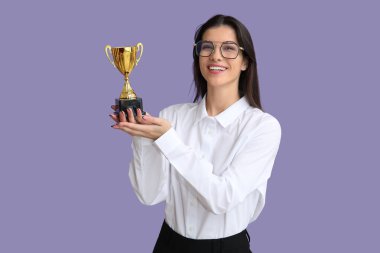 Leylak arka planında altın kupası olan genç bir iş kadını.