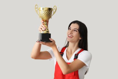 Hafif arka planda altın bardağı olan kadın işçi.