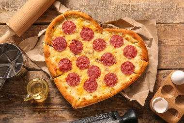 Lezzetli kalp şekilli pizza, yumurta ve ahşap arka planda yağ.