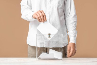 Bej arka planda oy sandığının yanındaki genç adam, yakın plan